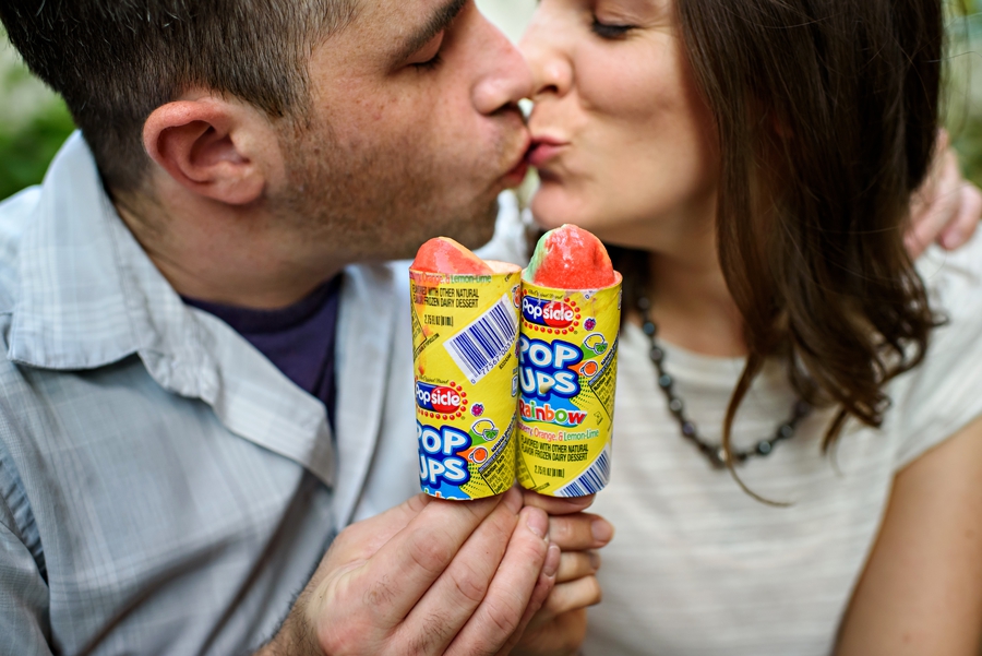 A cute engaged couple kiss while holding thier ice cream in fishtown.